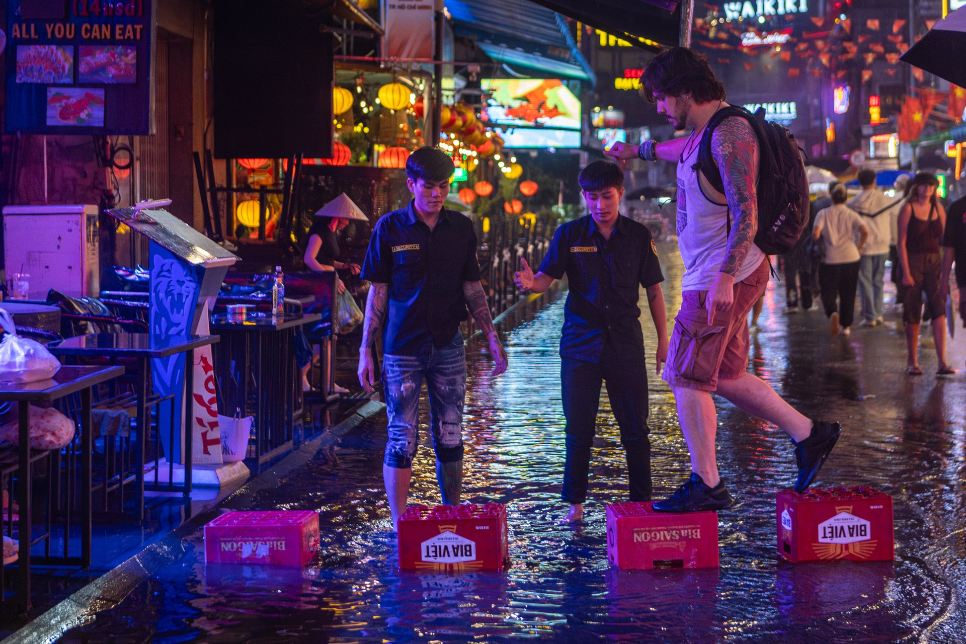 Một du khách được nhân viên quán hỗ trợ bước qua đoạn ngập.