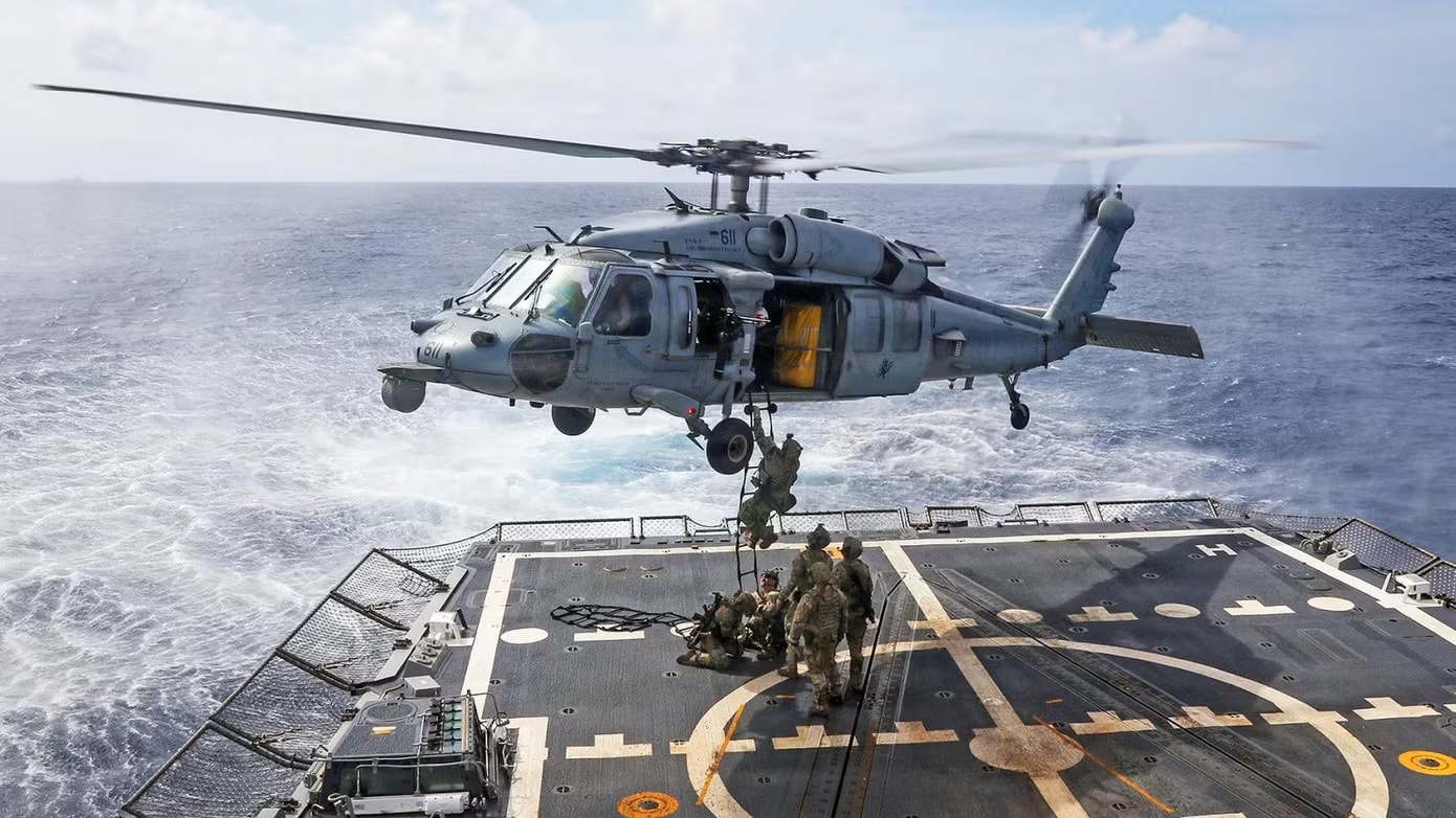 Các kỹ thuật viên xử lý vật liệu nổ lên trực thăng MH-60R Sea Hawk, thuộc Phi đội Trực thăng Tác chiến Biển 14, từ boong tàu khu trục tên lửa dẫn đường lớp Arleigh Burke USS Frank E. Petersen Jr. ngày 1/1/2026. Tàu Frank E. Petersen Jr. đang tiến hành các hoạt động thường lệ trong khu vực hoạt động của Hạm đội 7 Mỹ. Các đơn vị thuộc Hạm đội 7 thường xuyên tuần tra khu vực Ấn Độ Dương - Thái Bình Dương nhằm răn đe hành vi gây hấn, củng cố liên minh và quan hệ đối tác, cũng như thúc đẩy hòa bình thông qua sức mạnh. Ảnh: US Navy. Ngoài phong tỏa, Mỹ săn đuổi các tàu liên quan Iran trên toàn cầu, 'bảo đảm Tehran không bao giờ có vũ khí hạt nhân' - Ảnh 1.