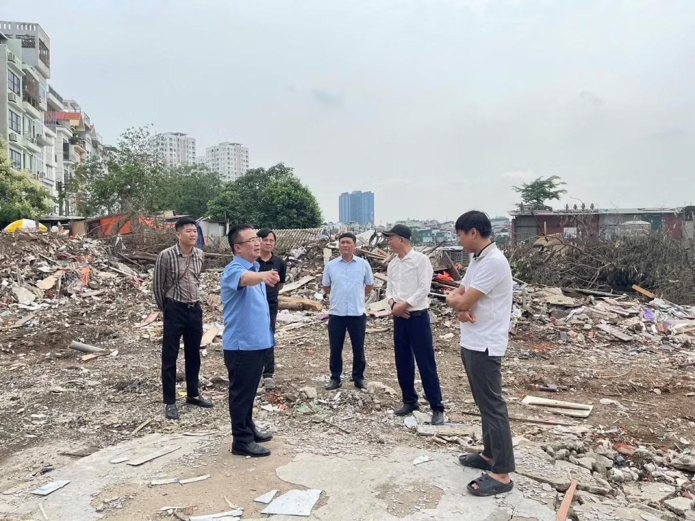 Chủ tịch UBND phường Khương Đình Nguyễn Sỹ Đoàn (áo xanh) kiểm tra, đôn đốc tiến độ giải phóng mặt bằng và thi công xây dựng công trình. Đường Vành đai 2,5: Các phường bắt đầu bàn giao đất đã GPMB để thi công - Ảnh 1.