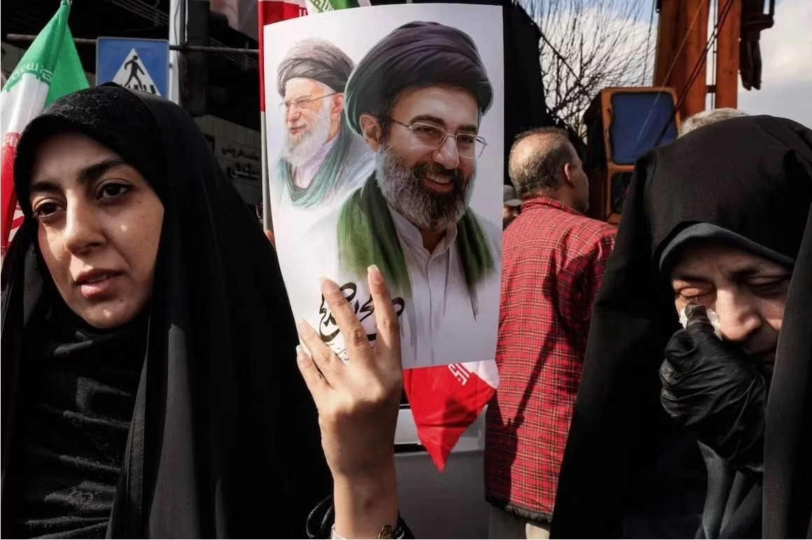 Người dân Iran cầm ảnh chân dung cố Lãnh tụ tối cao Ali Khamenei và Lãnh tụ tối cao đương nhiệm Mojtaba Khamenei. (Ảnh: Asia Times) Iran chiến thắng theo cách của mình - Ảnh 1.