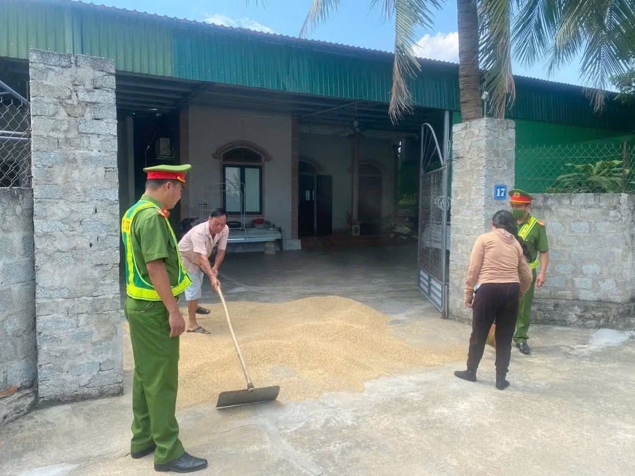 Công an yêu cầu bà Q. gom lúa phơi giữa đường. Ảnh: CACC Phơi lúa lấn đường, người phụ nữ dùng cào chặn xe tải, tấn công tài xế - Ảnh 2.