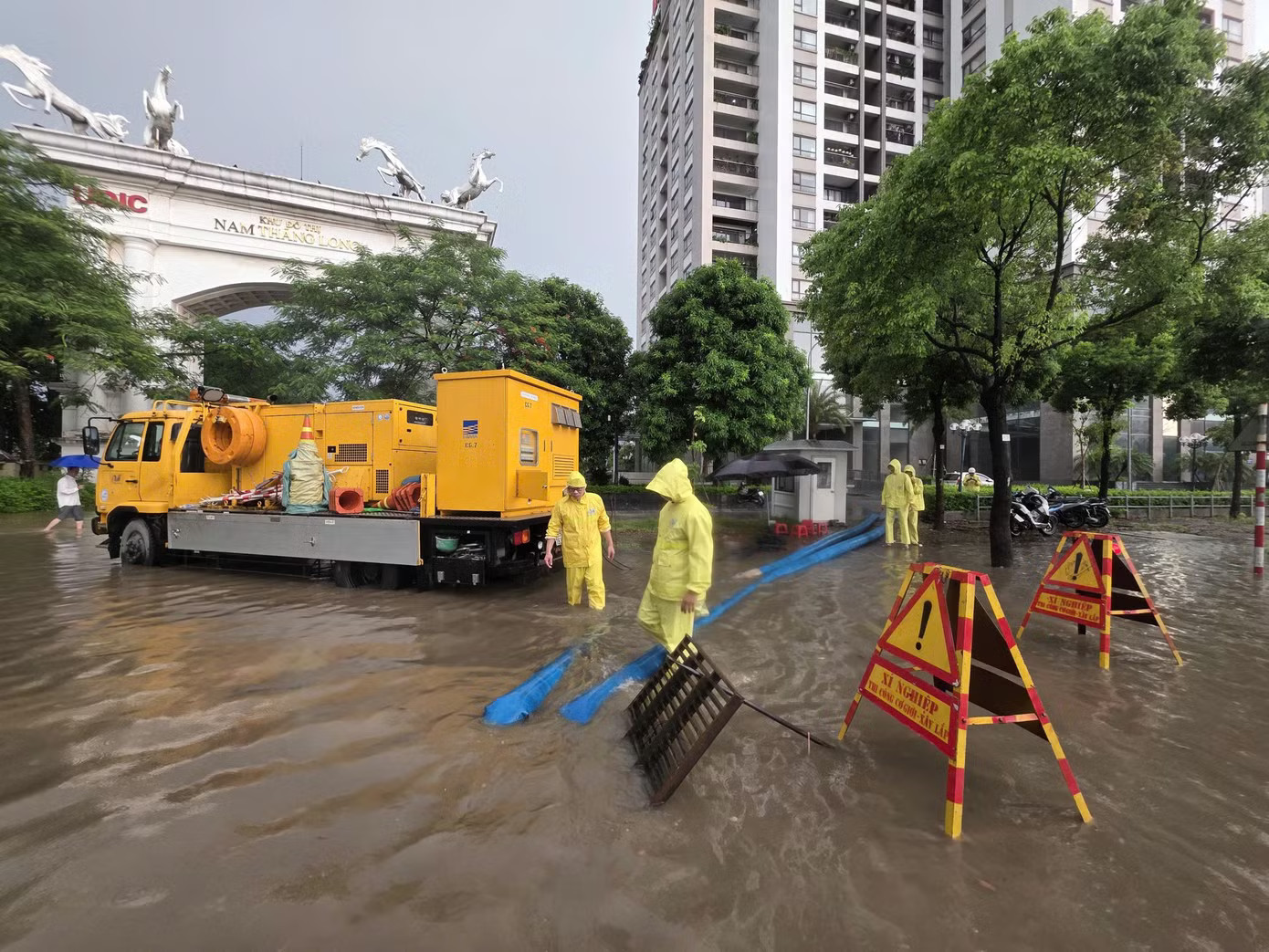 Lực lượng thoát nước ứng trực, vận hành máy bơm hạ mực nước tại khu vực đường Võ Chí Công sáng 25/7. Vì sao đường Võ Chí Công vẫn ngập sâu 30cm sau trận mưa rạng sáng 25/7? - Ảnh 1.